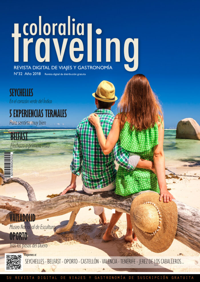a man and woman sitting on a log on a beach traveling32